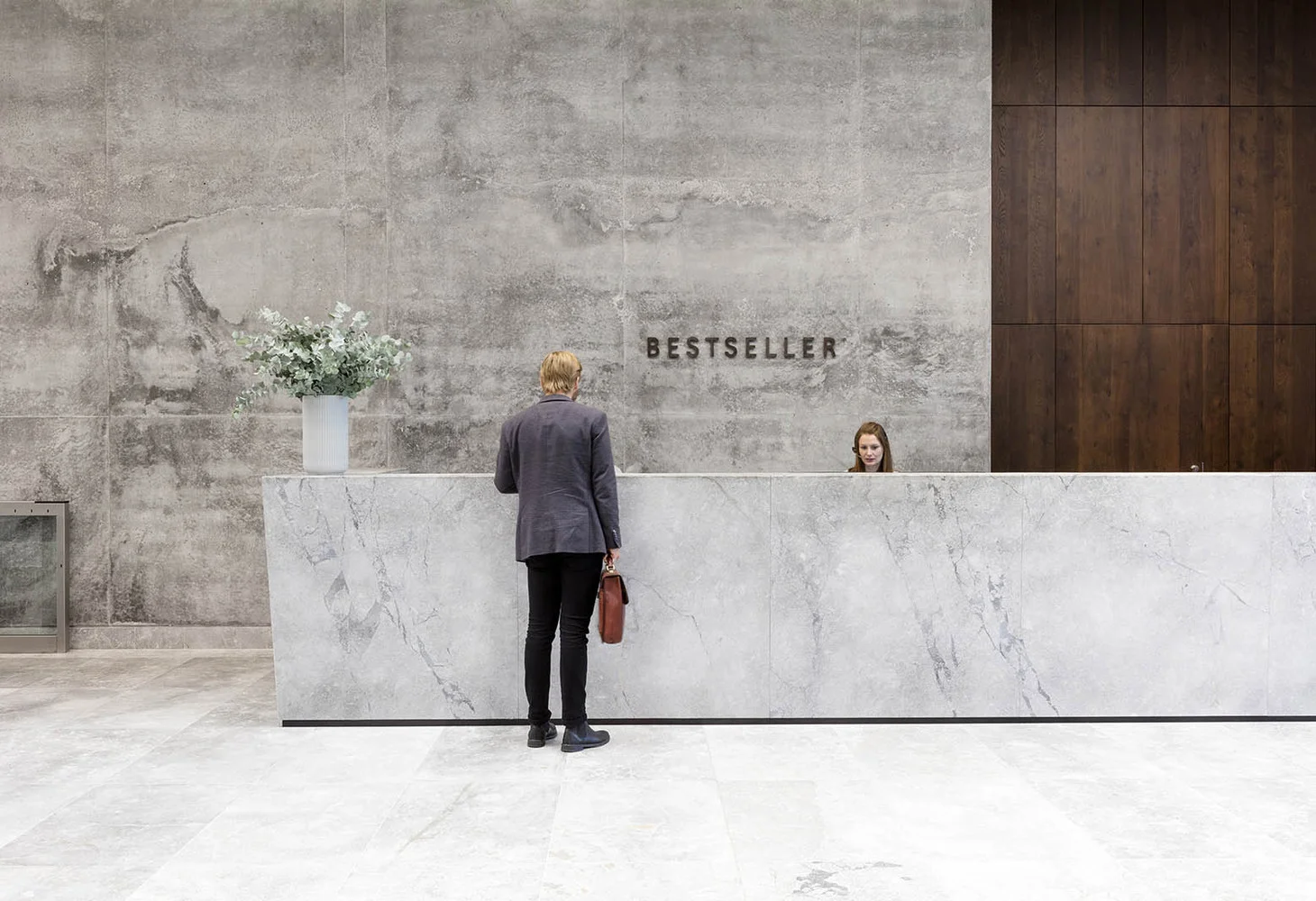 A visitor approaching a marble reception desk